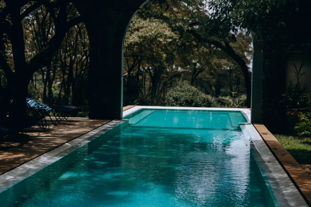 A turquoise swimming pool surrounded by tropical gardens